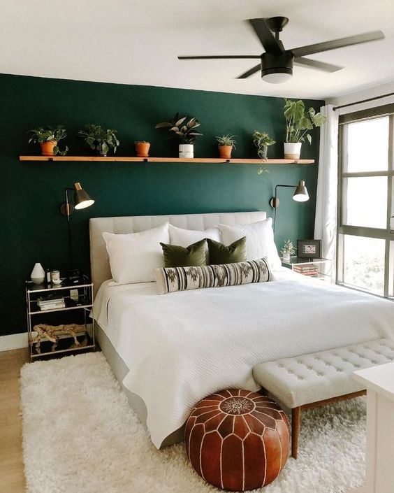 Green accent wall with plants in a bedroom