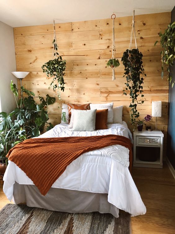 Rustic boho bedroom with natural wood accent wall and house plants