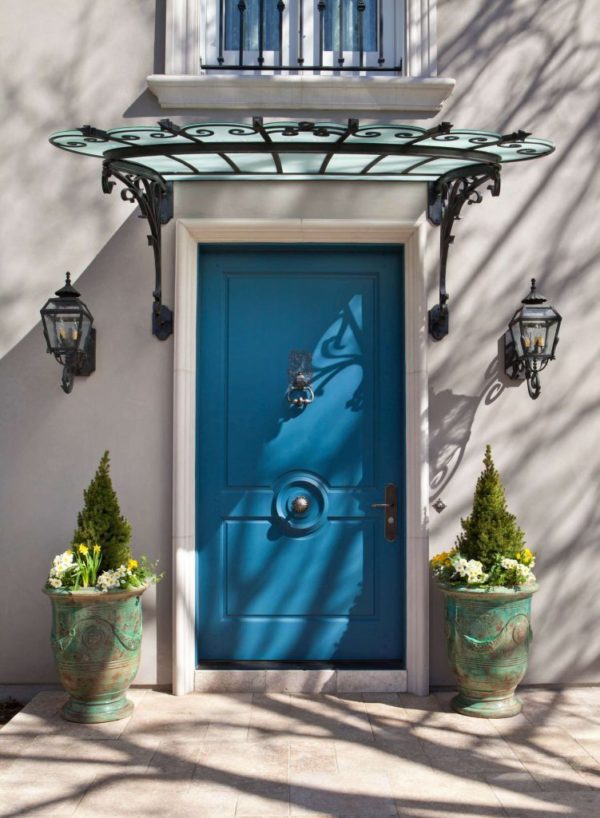 Elegant entryway -Blue Front Door, antique awning, two french style wall lights, and two planters