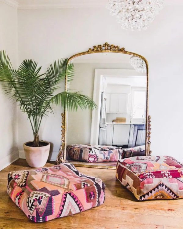 Minimalist bohemian decor with large vintage mirror, crystal chandelier and ethnic poufs