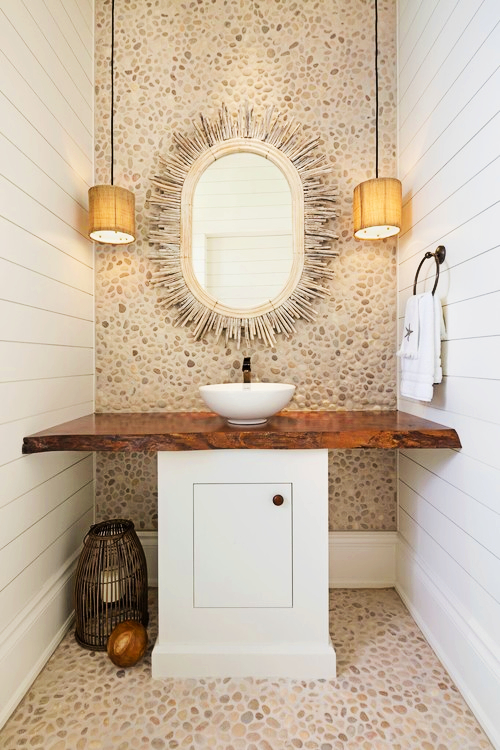 coastal style bathroom with pebbled wall and float wood starburst mirror and pendant lights