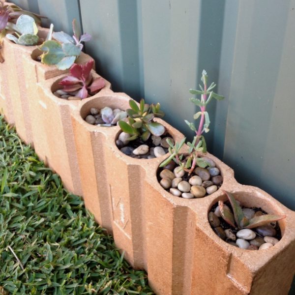 Garden bed edging with bricks , succulents and pebbles