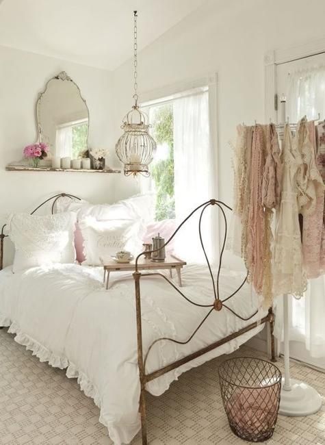 Modern shabby chic bedroom with mirror headboard, metal bed, chandelier and a bird cage